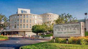 Main entrance of Valley Presbyterian Hospital in Van Nuys, with the hospital's curved tower behind the entrance sign.